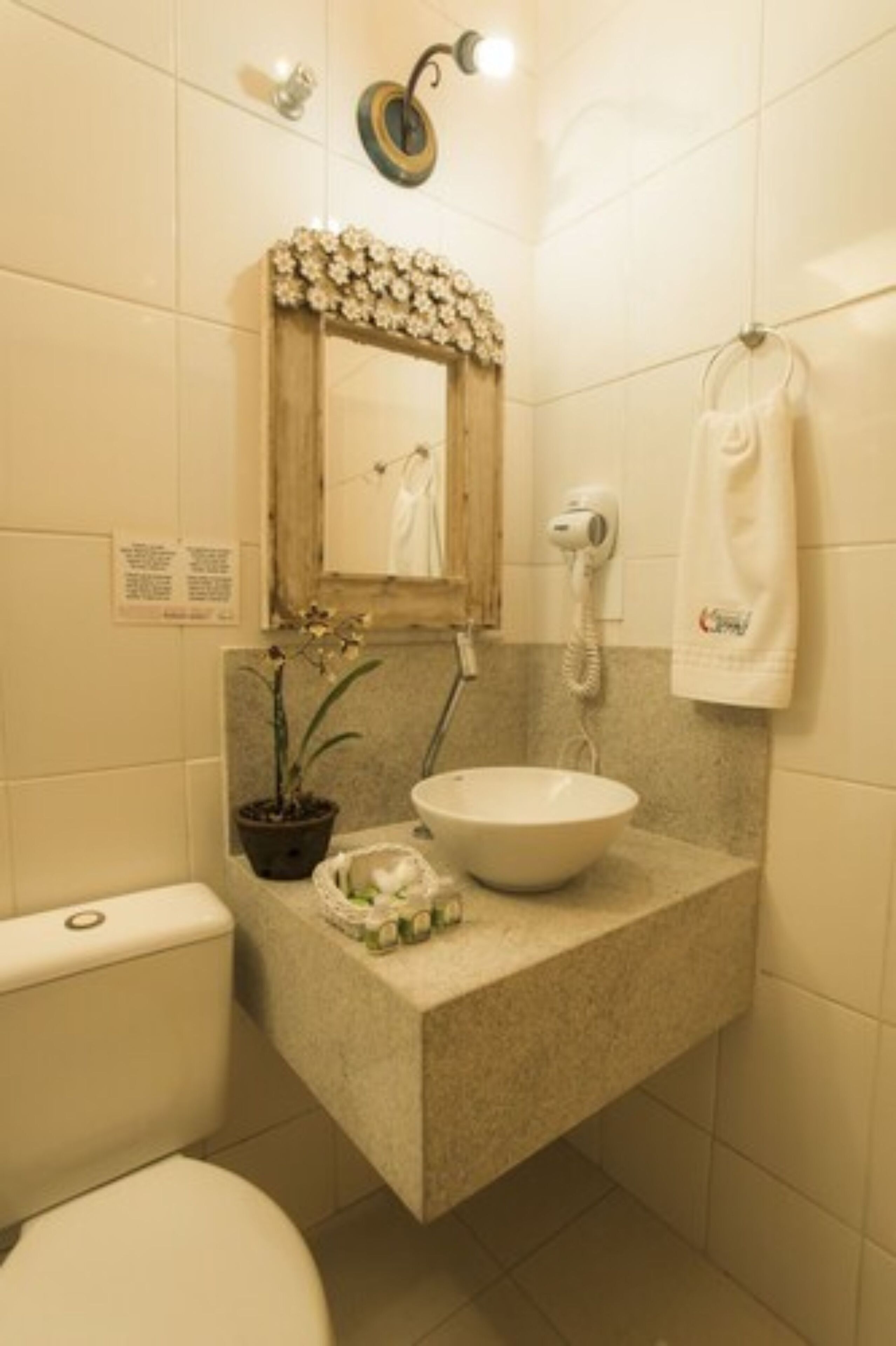 Un baño con inodoro, lavamanos, espejo y toallero.