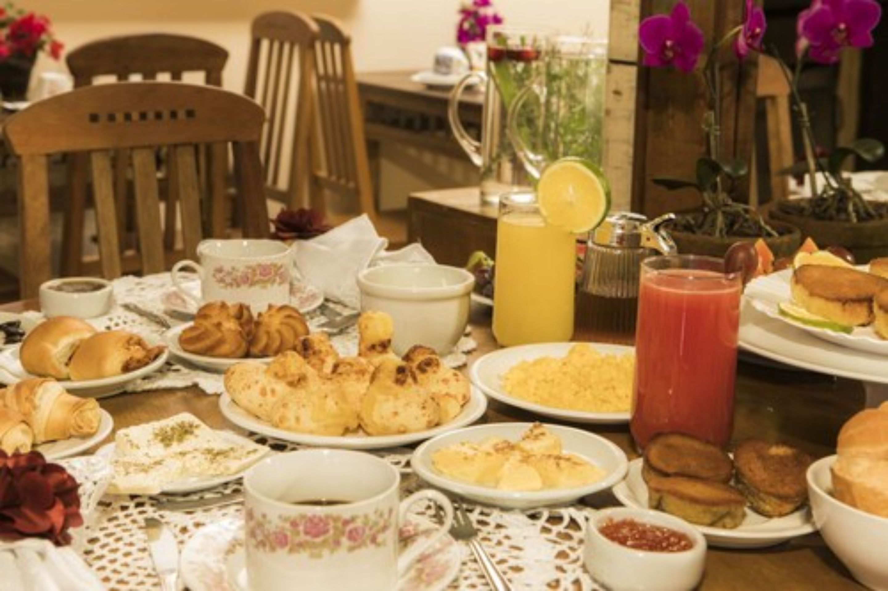 A breakfast table with various pastries, a pitcher of orange juice, and a glass of red juice.