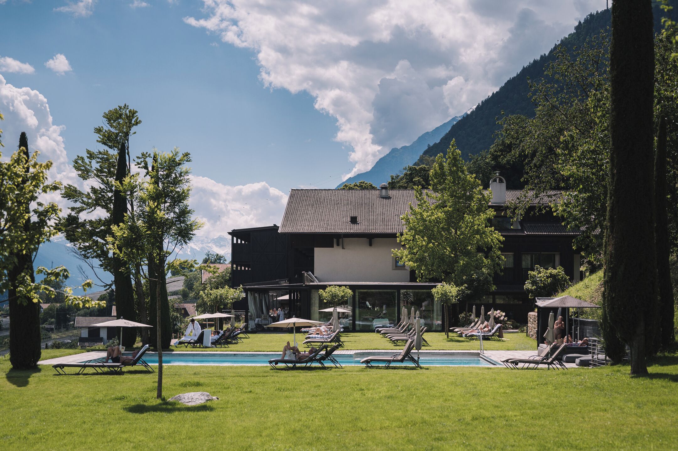 Una piscina al aire libre, sombrillas, sillones reclinables de piscina