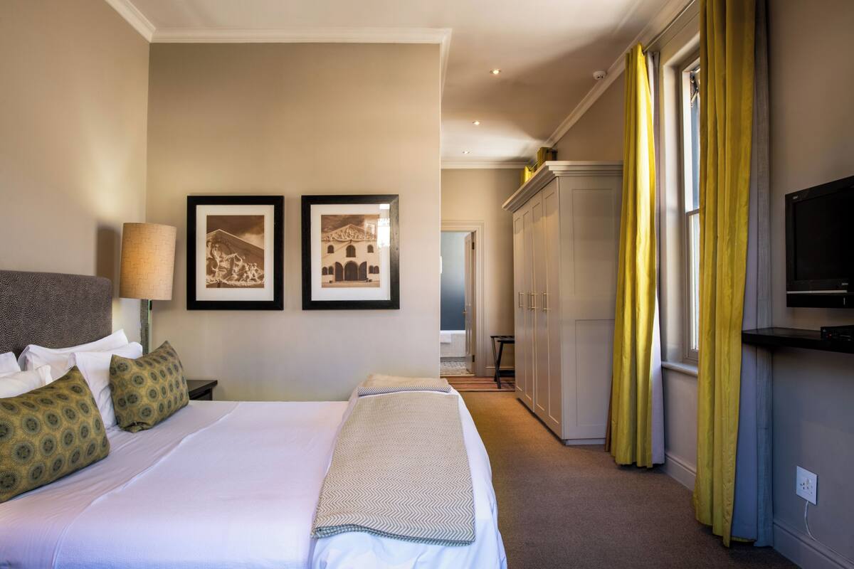 Habitación de hotel con dos camas, un televisor, un armario y un cuadro en la pared.
