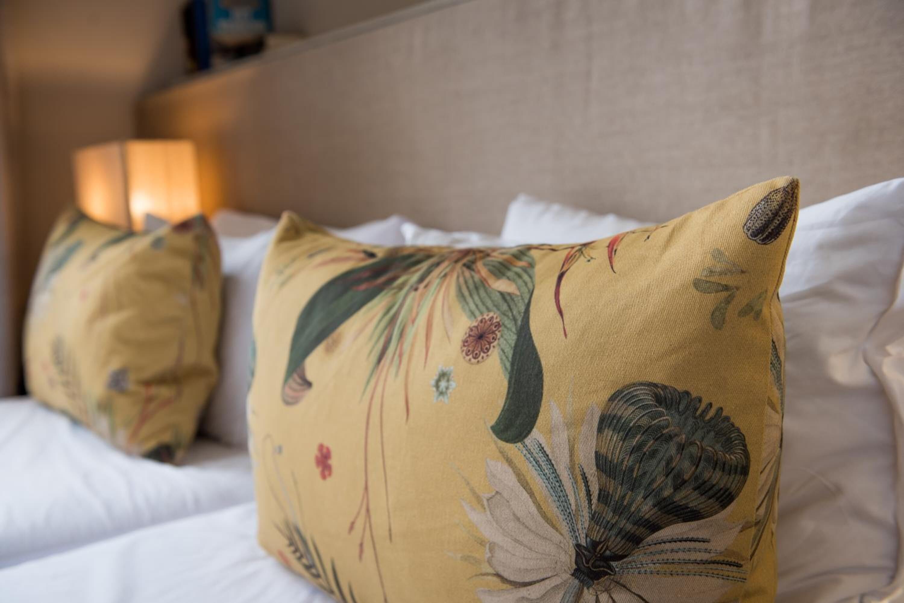 Un lit avec des oreillers à motifs floraux et une tête de lit.