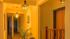 A hallway with a wooden railing, potted plants, and hanging lanterns. - Pousada Ramalhete (Tiradentes)