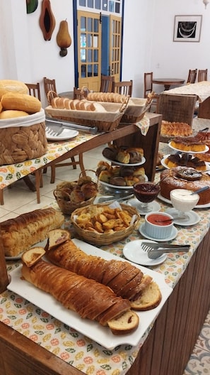 A buffet table with various breads and pastries. - Pousada Ramalhete (Tiradentes)