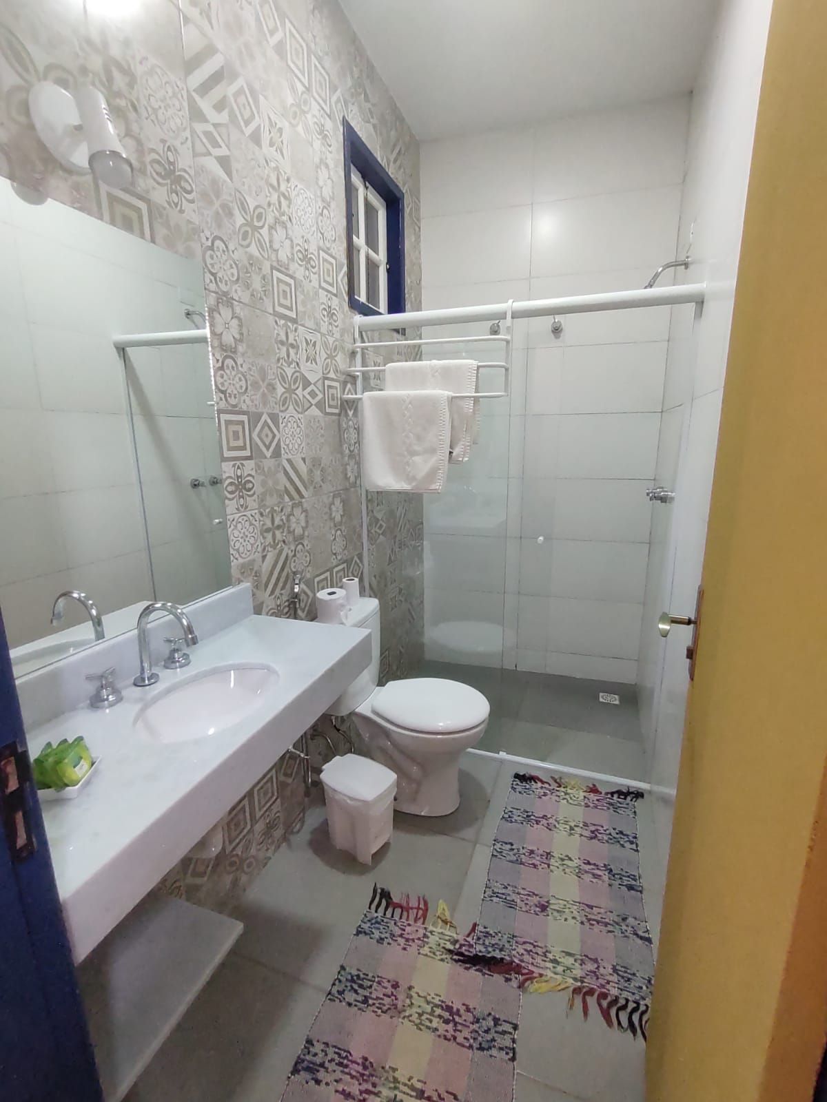 A bathroom with a white sink, a toilet, a shower, and a patterned floor.