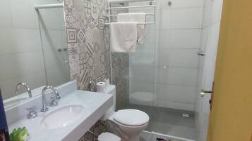 A bathroom with a white sink, a toilet, a shower, and a patterned floor.