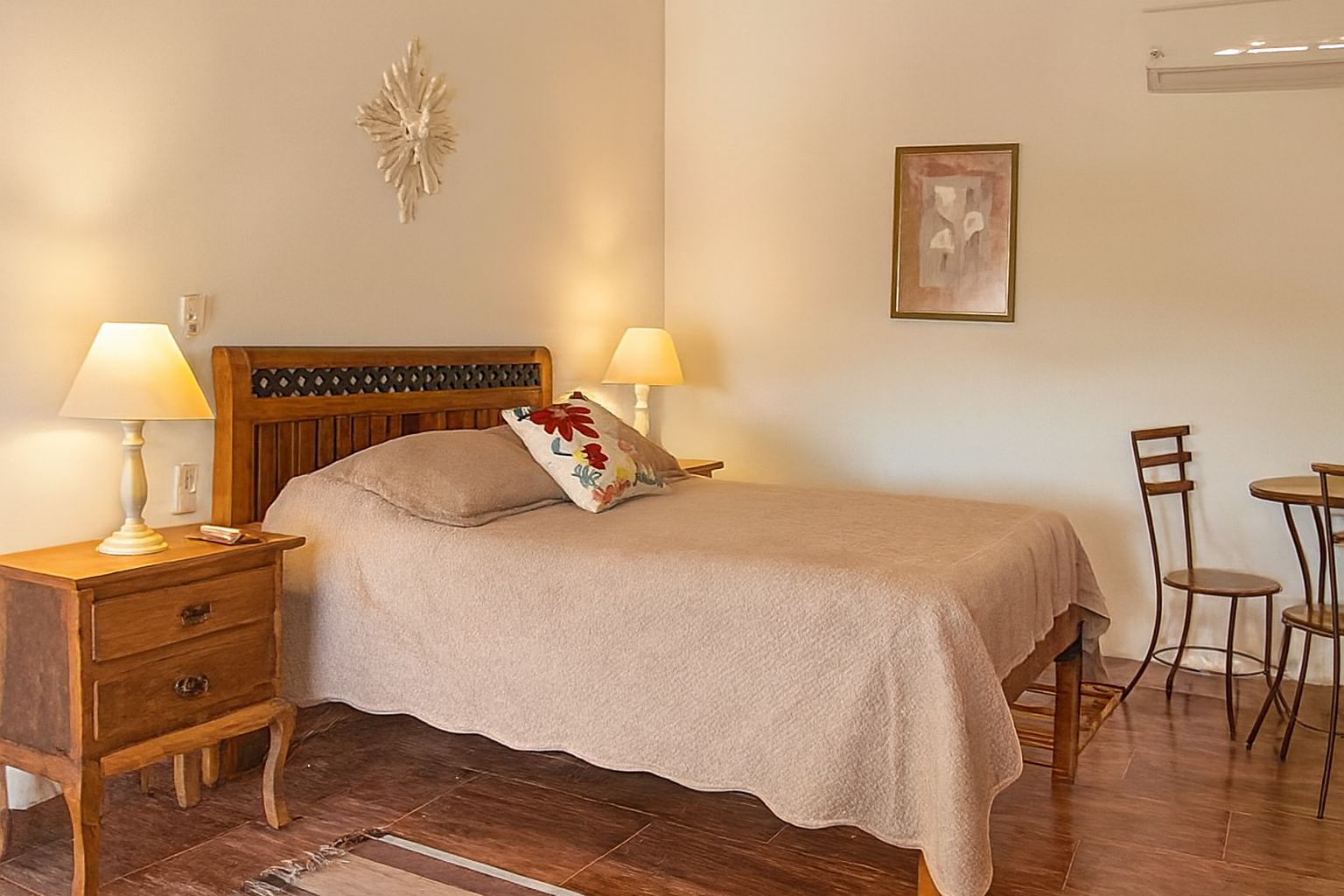 A bedroom with a bed, two bedside tables with lamps, a chair, and a small table.
