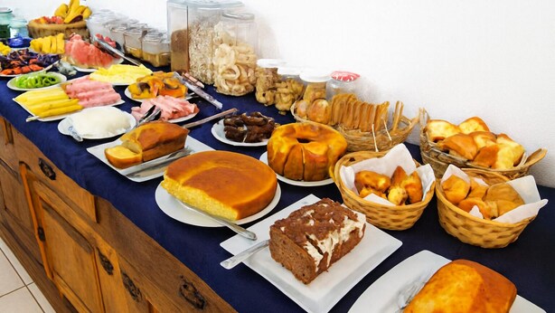 A buffet table with various food items including cakes, pastries, and fruits. - Pousada Ramalhete (Tiradentes)