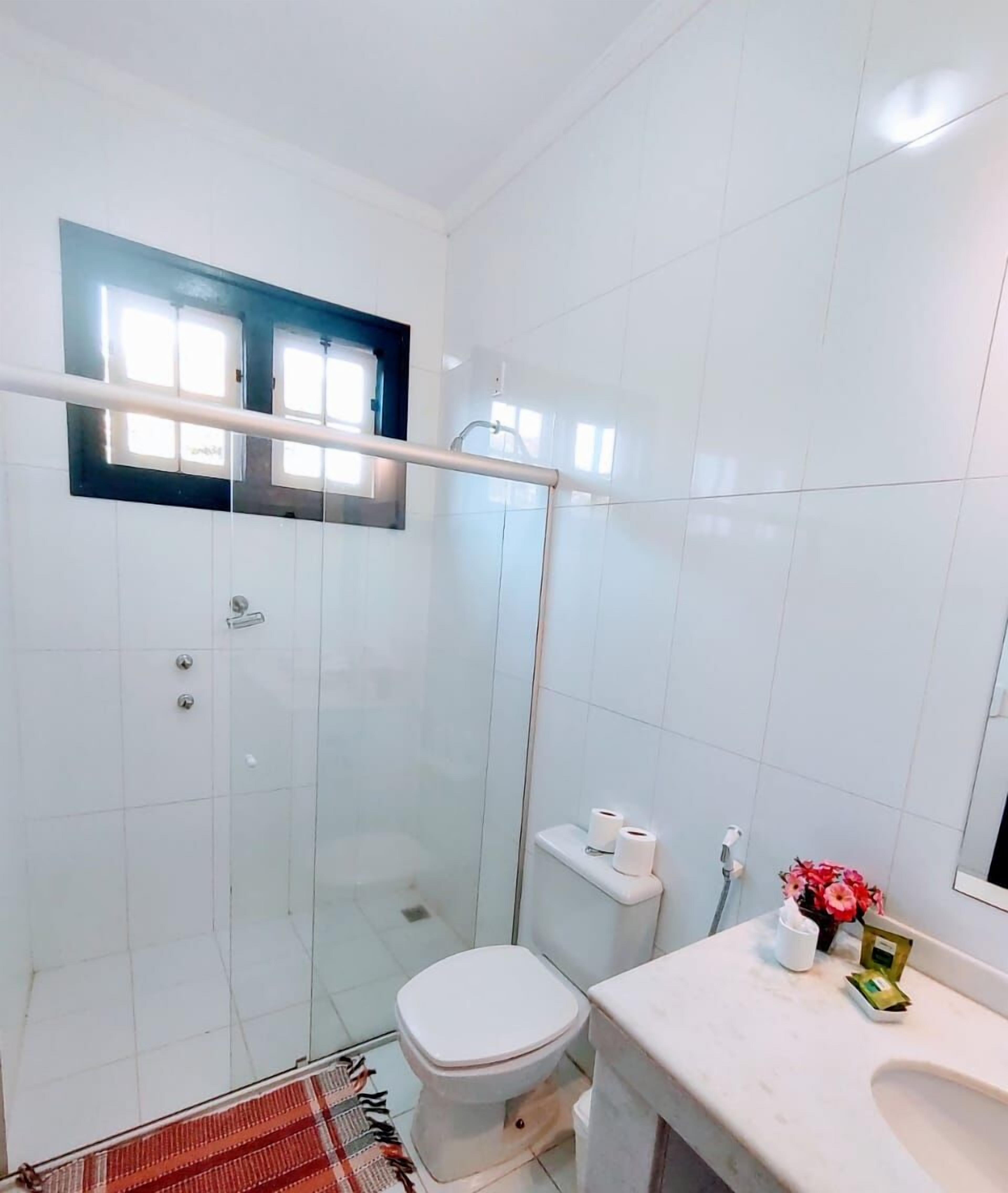 A modern bathroom with a glass-enclosed shower, a toilet, and a sink with a mirror.