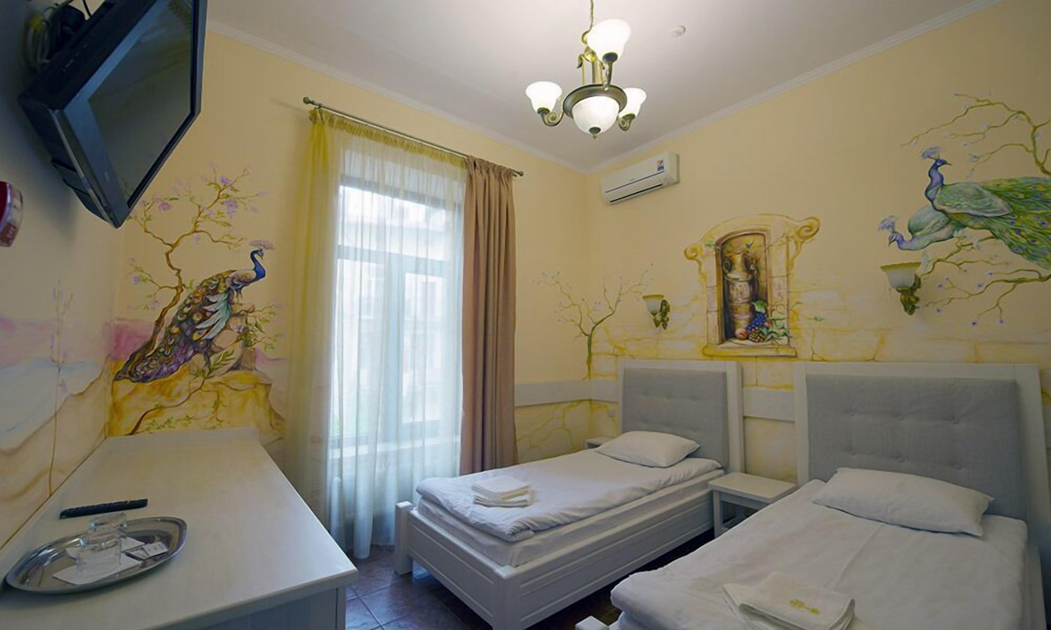 Habitación de hotel con dos camas, televisión, candelabro y decoración en la pared.