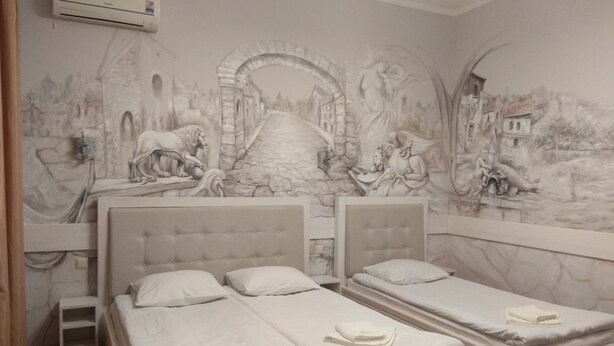 A hotel room with two beds, a mural on the wall, and an air conditioning unit. - Apart Hotel Na Dobu (Lviv)