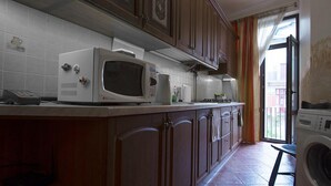 A kitchen with a microwave, coffee maker, and washing machine. - Apart Hotel Na Dobu (Lviv)