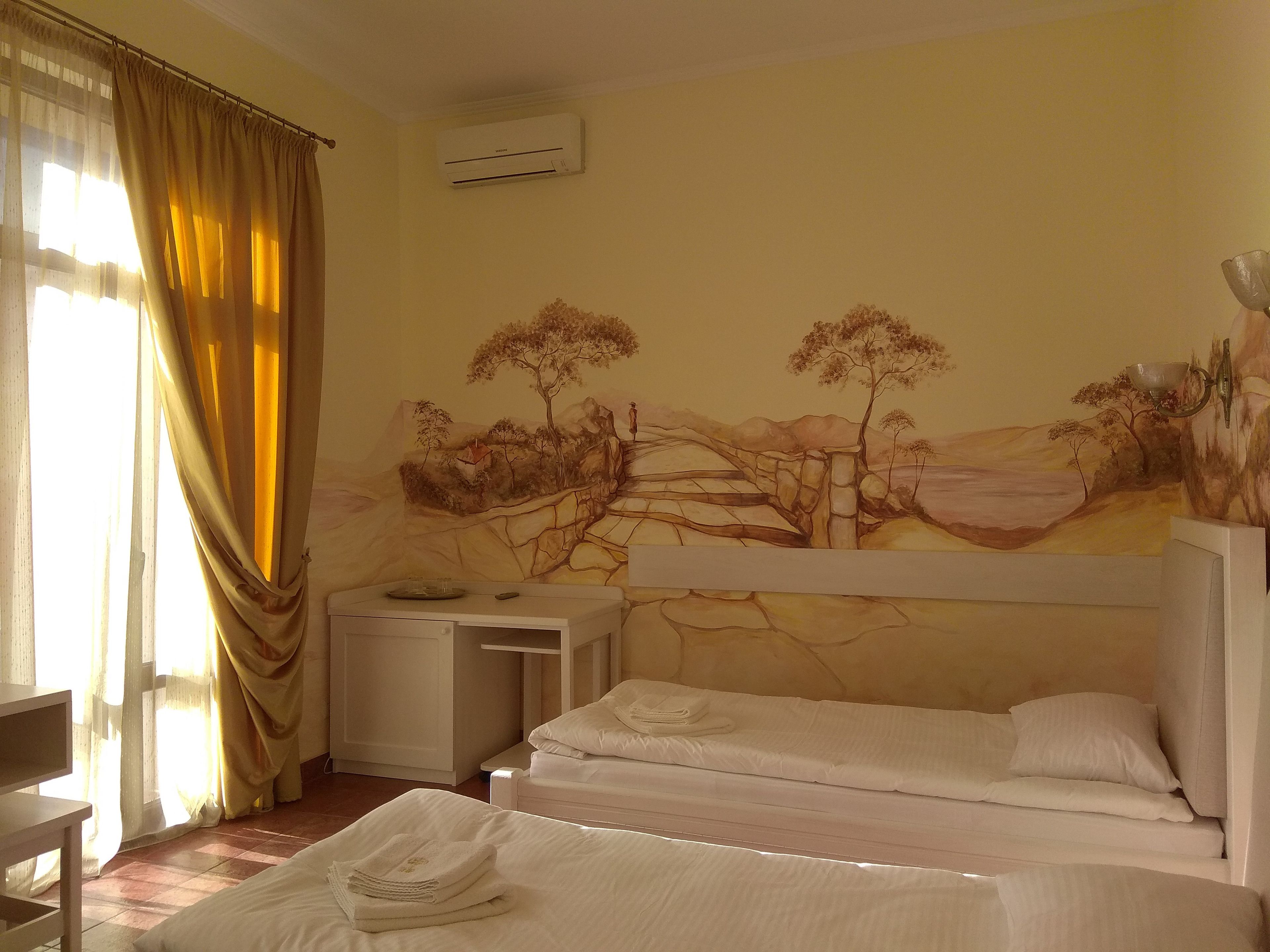 Una camera d'albergo con due letti, una scrivania e un quadro appeso al muro.