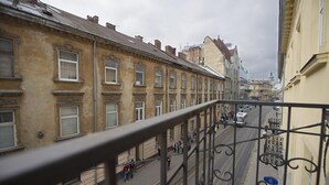 A view from a balcony overlooking a street with buildings, a tram, and pedestrians. - Apart Hotel Na Dobu (Lviv)