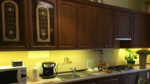 A kitchen with wooden cabinets, a microwave, a coffee maker, a sink, and a stove. - Apart Hotel Na Dobu (Lviv)