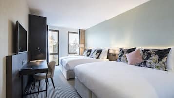 Habitación de hotel con dos camas, un escritorio y un televisor.