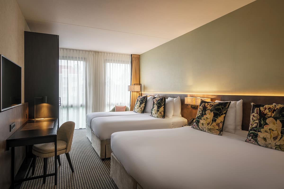 Ett hotellrum med två sängar, ett skrivbord, en stol och en TV.