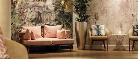 A modern hotel lobby with a large mural of the Eiffel Tower, a plush sofa, two armchairs, a coffee table, and a large potted plant.