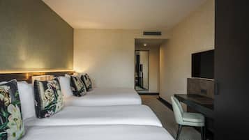 Quarto de hotel com duas camas, uma escrivaninha, uma cadeira e uma televisão.