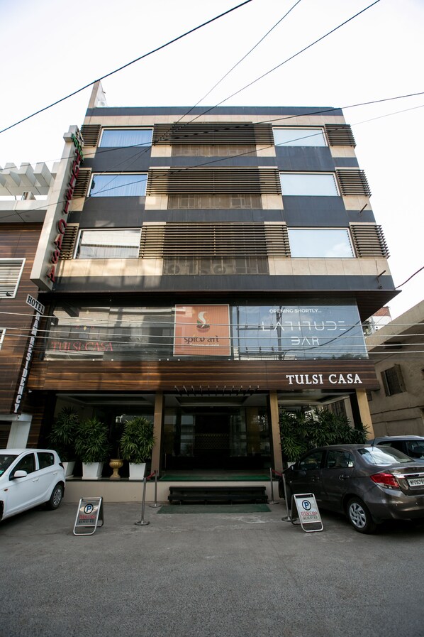 A multi-story building with a sign for 'Tulsi Casa' indicating a hotel or guesthouse. There are two cars parked in front, and a 'P' parking sign is visible. - Tulsi Casa (Bhopal)