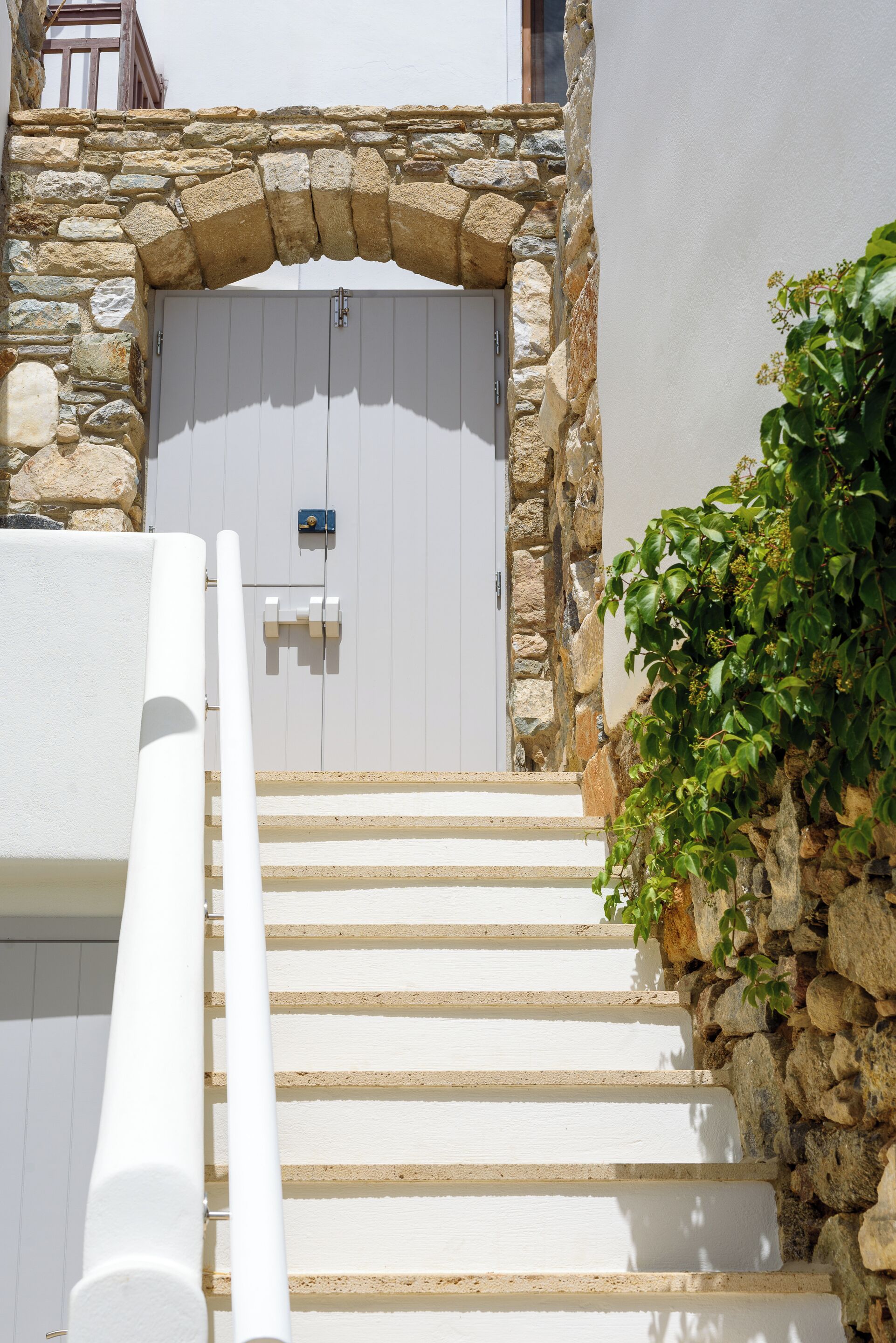 A stone archway leading to a white door with a small sign above it.