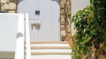 A stone archway leading to a white door with a small sign above it.