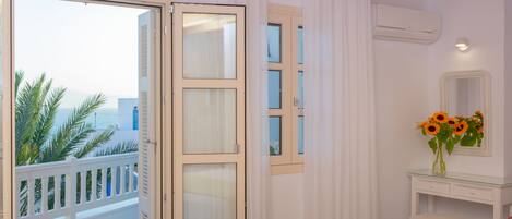 A bedroom with a balcony, a bed, a dresser, and a mirror.