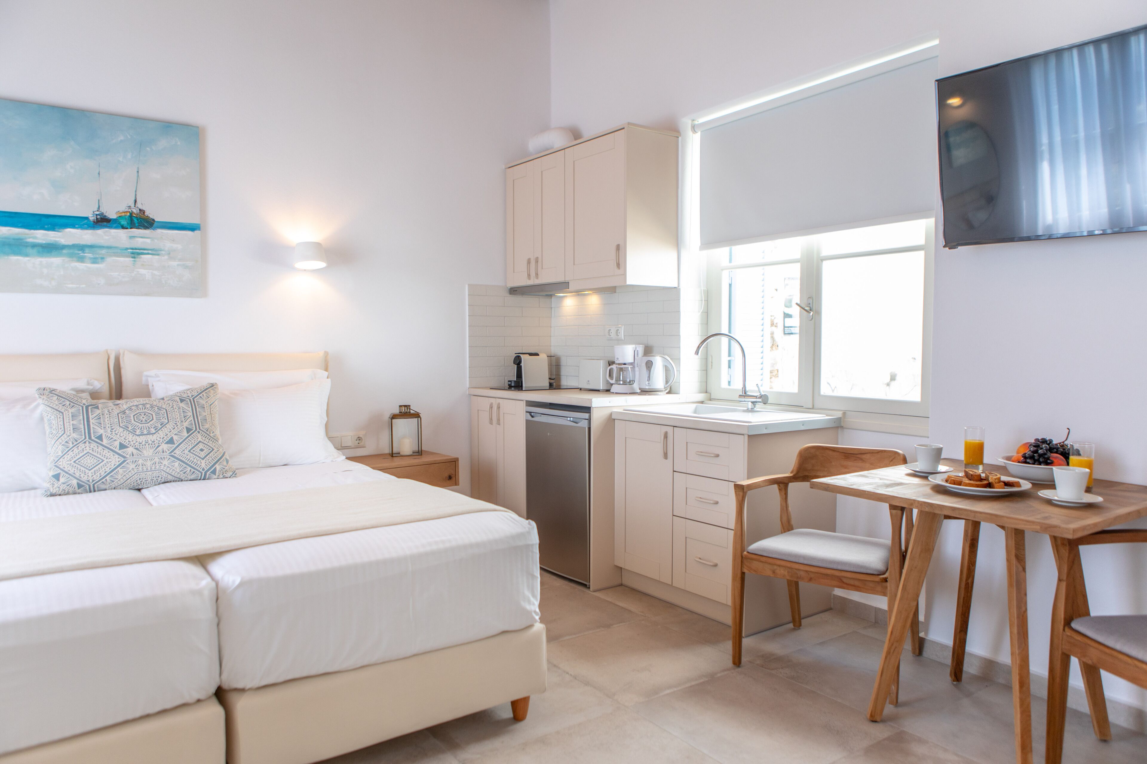 A modern bedroom with a bed, bedside table, and a painting of boats on the wall.