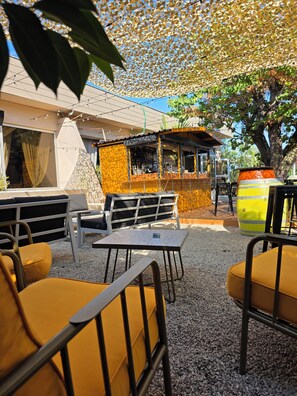 An outdoor seating area with tables and chairs, a bar area, and a decorative canopy. - Logis Hôtel Restaurant Le Pardaillan (Gondrin)