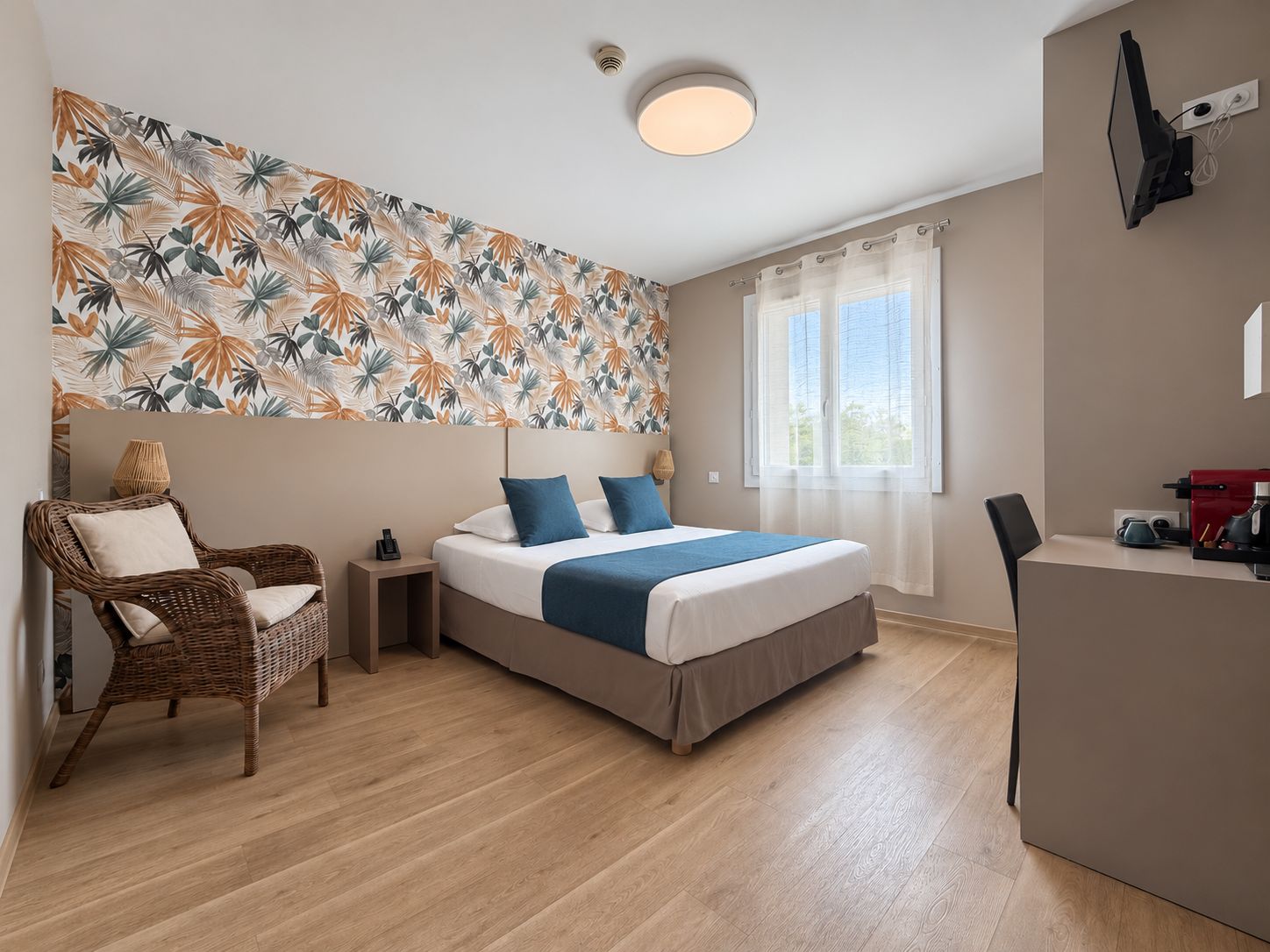 Ein Hotelzimmer mit Bett, Stuhl, Schreibtisch und Fenster.