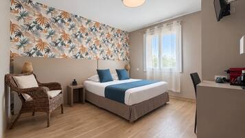 Ein Hotelzimmer mit Bett, Stuhl, Schreibtisch und Fenster.