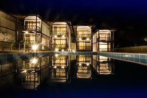 A modern hotel with a pool reflecting its architecture.