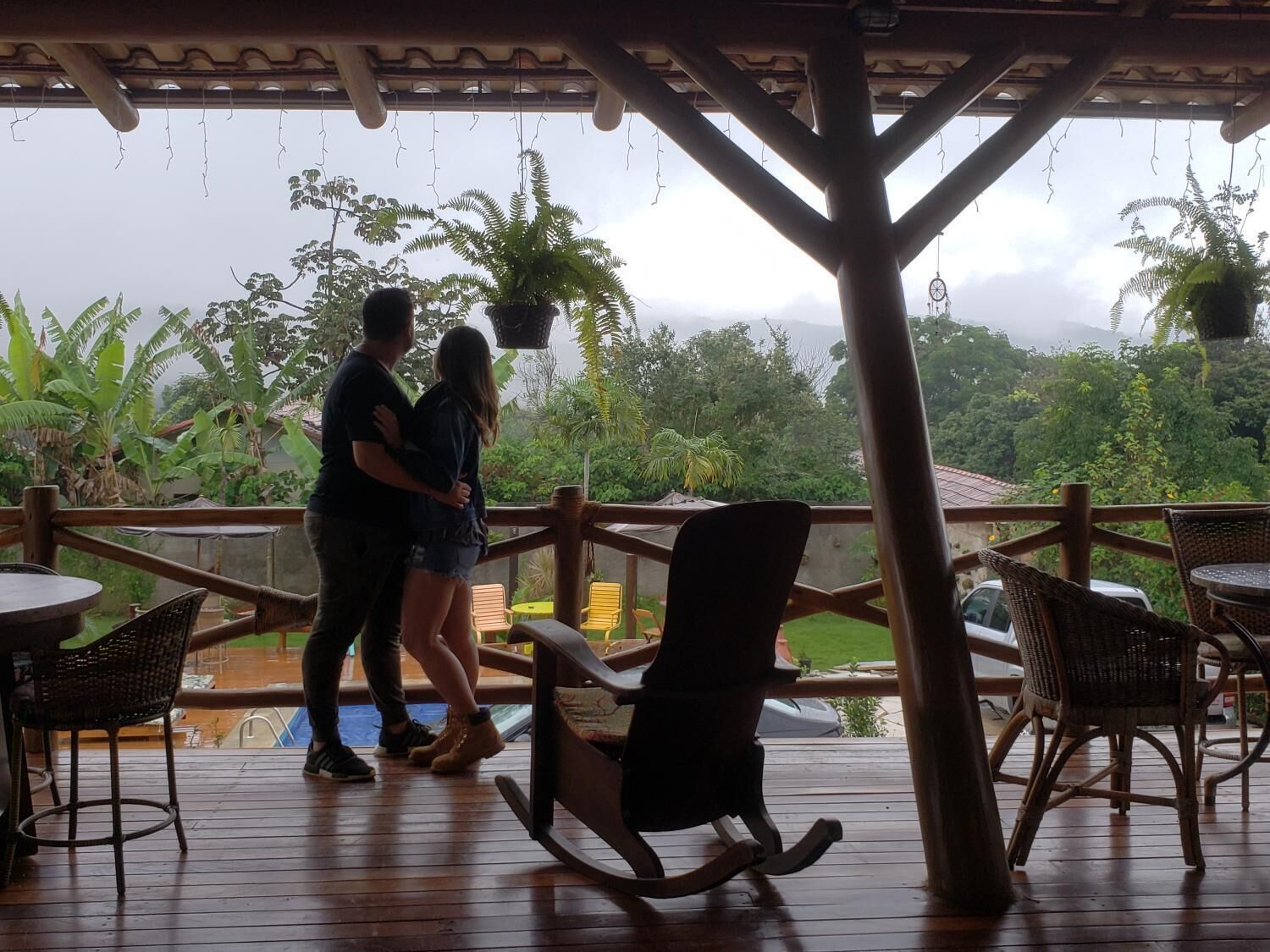A couple dancing on a wooden deck with outdoor seating and potted plants.