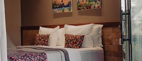 A bedroom with a bed, a brick wall, and two paintings.