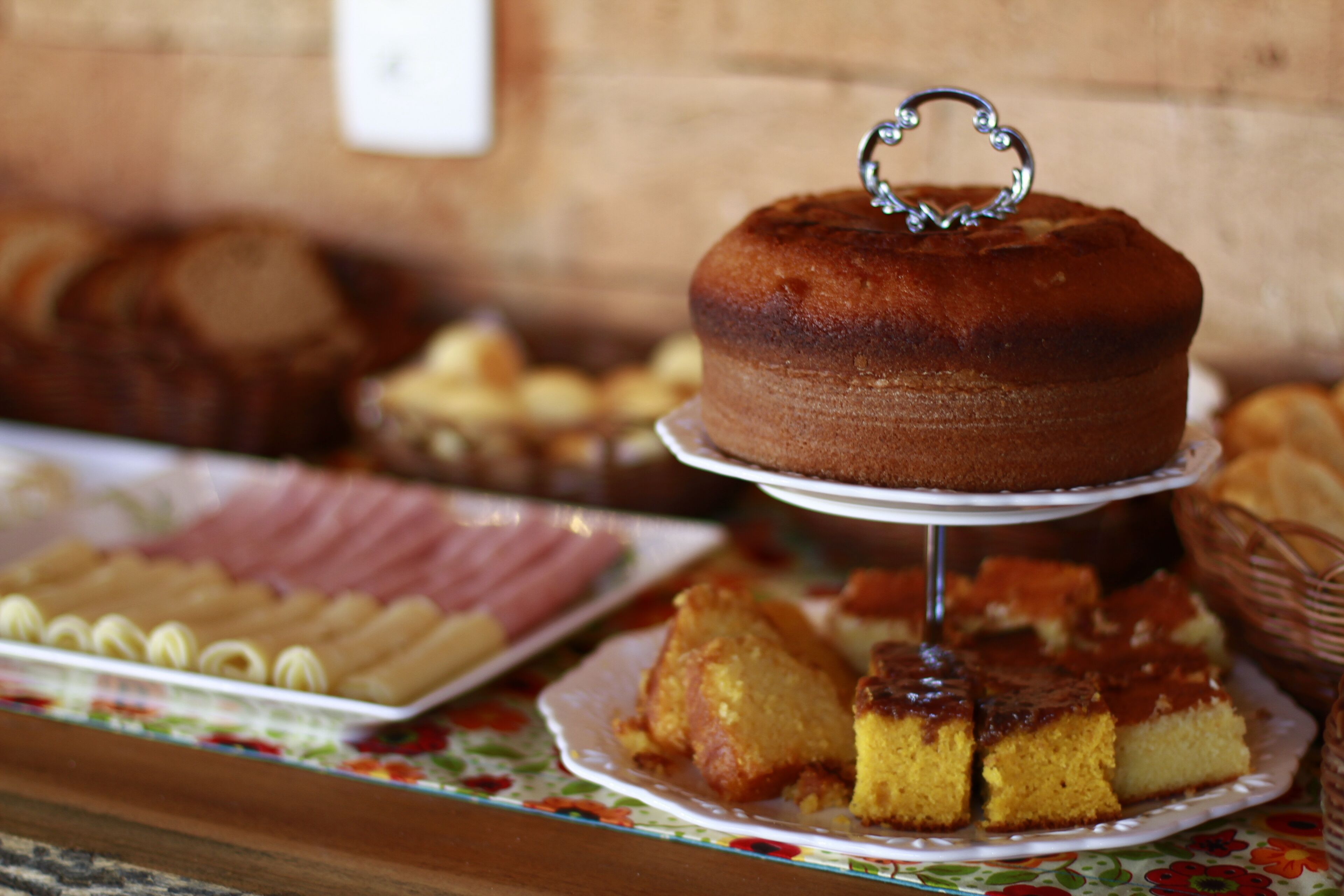 Ein Kuchen auf einem Sockel mit Herz-Topper, umgeben von anderen Desserts auf einer Tischplatte.