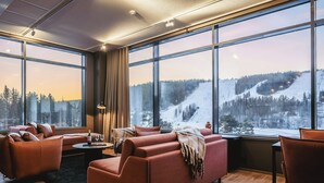 A modern interior with large windows, a sofa set, and a view of a snowy landscape.