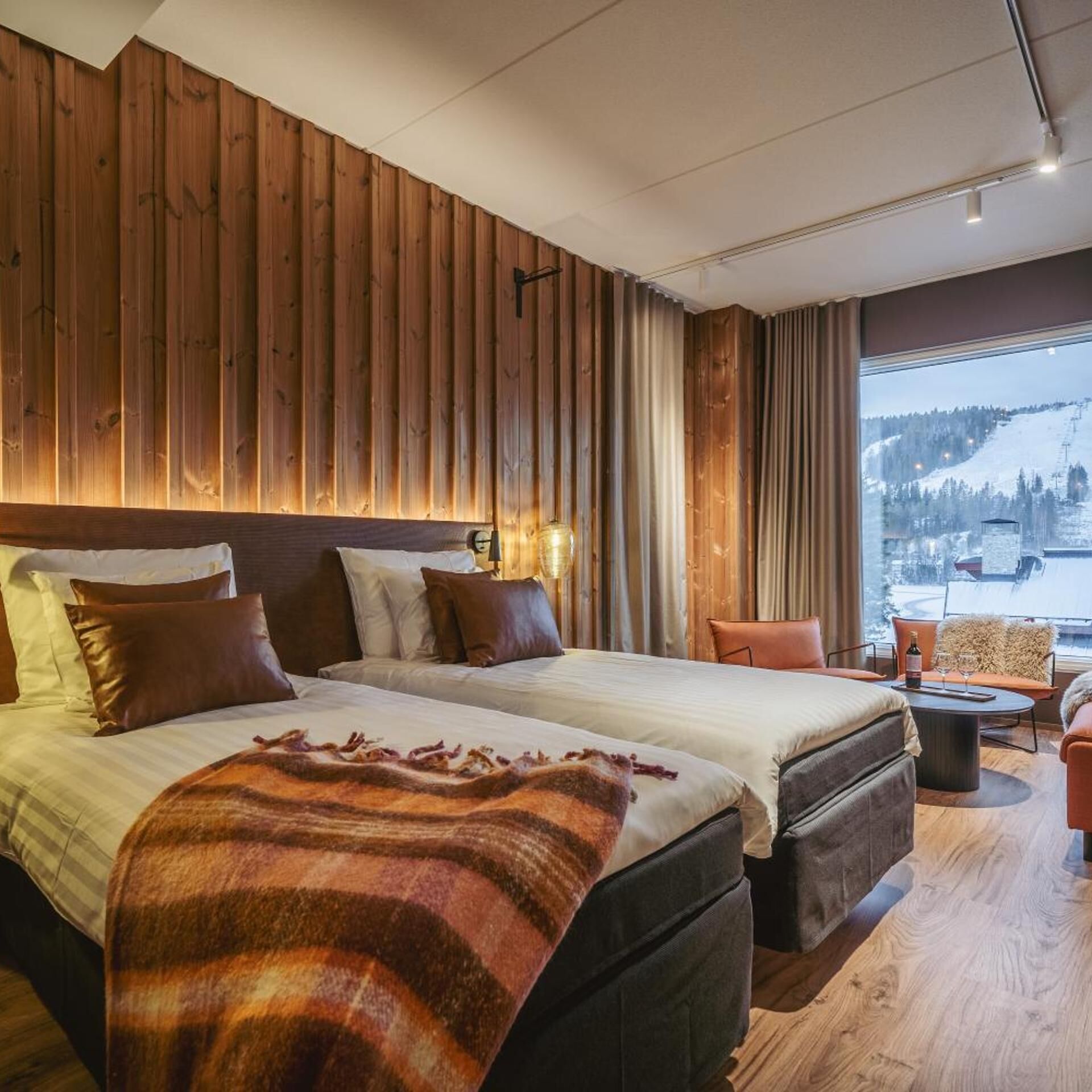 A hotel room with a large bed, a seating area with a view of a snowy landscape.
