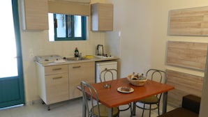 Une cuisine compacte avec un coin repas, comprenant un évier, une cuisinière et une table à manger avec des chaises.