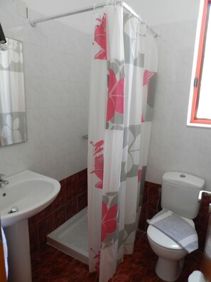 A bathroom with a shower curtain, a sink, and a toilet.