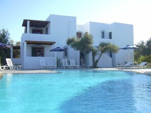 A modern building with a pool, white walls, and lounge chairs. - Triantafillas Appartments (Rhodes)