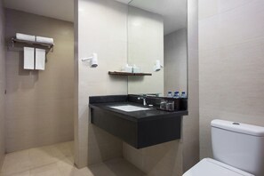 Une salle de bain moderne avec un lavabo noir, des toilettes blanches et un miroir au-dessus du lavabo. Deux serviettes blanches sont suspendues à un porte-serviettes, et une étagère contient des articles de toilette.