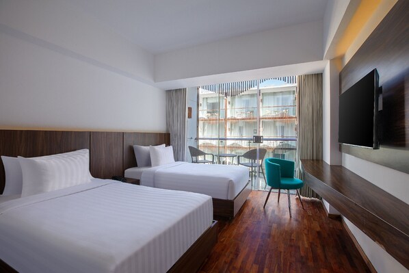 A hotel room with two beds, a TV, a balcony with a view, and a chair.