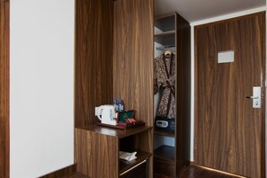A wooden wardrobe with a shelf containing a kettle, bottles, and a radio. - The Bene Kuta Bali (Kuta)
