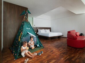 A room with a bed, a red chair, and a green tent-like structure with children reading. - The Bene Kuta Bali (Kuta)
