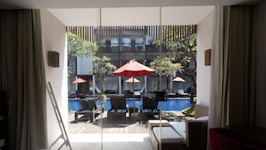 A hotel room with a view of an outdoor pool area, including lounge chairs and umbrellas. - The Bene Kuta Bali (Kuta)