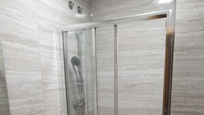 A modern bathroom with a glass-enclosed shower, a toilet, and a sink.