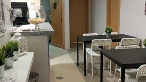 A compact kitchen with a dining area, white chairs, and potted plants.