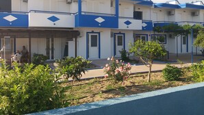 Un immeuble comprenant plusieurs logements à louer, avec une décoration aux couleurs bleu et blanc, et un petit jardin agrémenté de plantes et de fleurs.