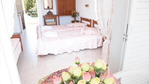 Une chambre à coucher avec un lit, une armoire en bois, une petite table avec une lampe et un vase rempli de fleurs.