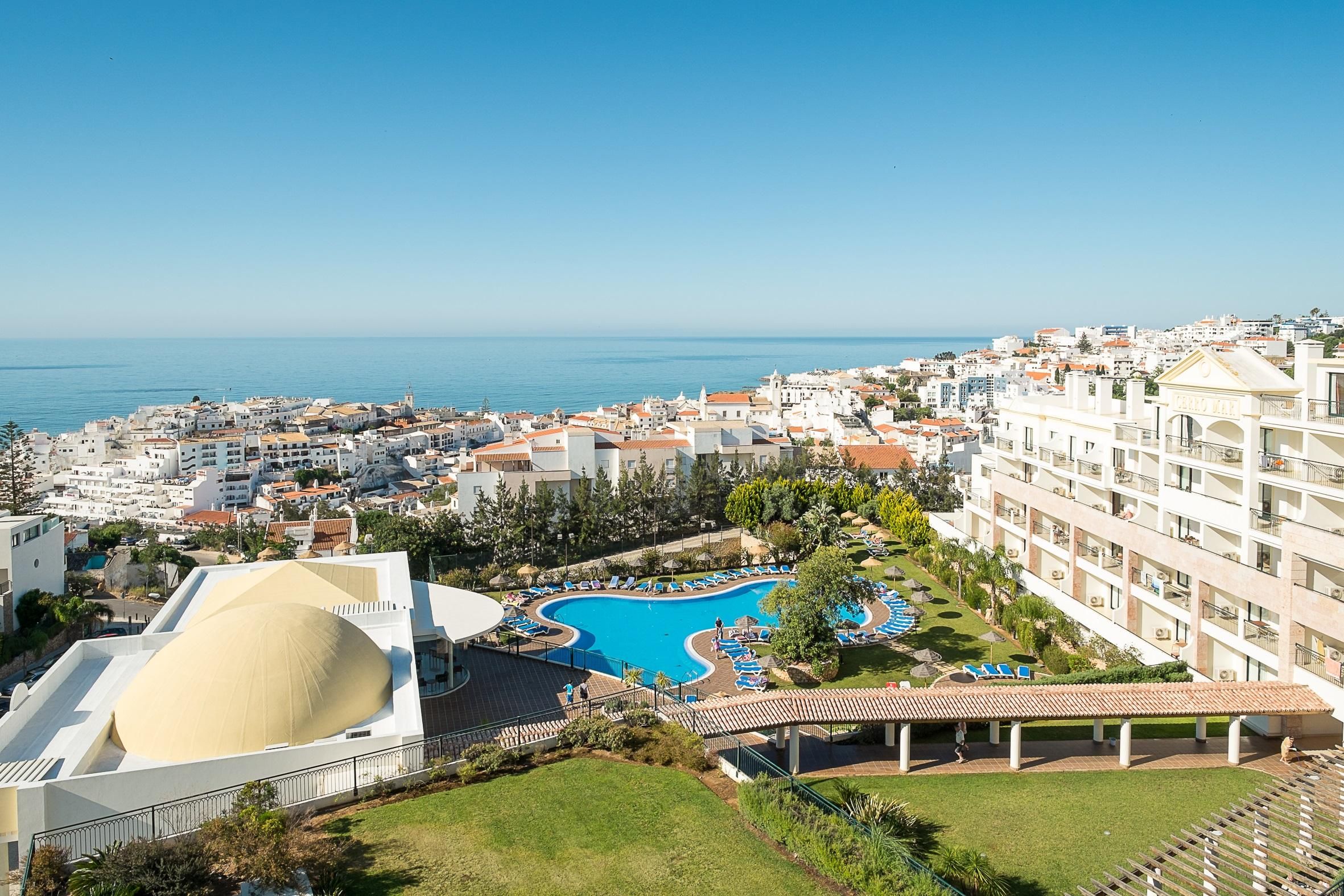 A resort with a large swimming pool, a covered area, and a view of the sea.