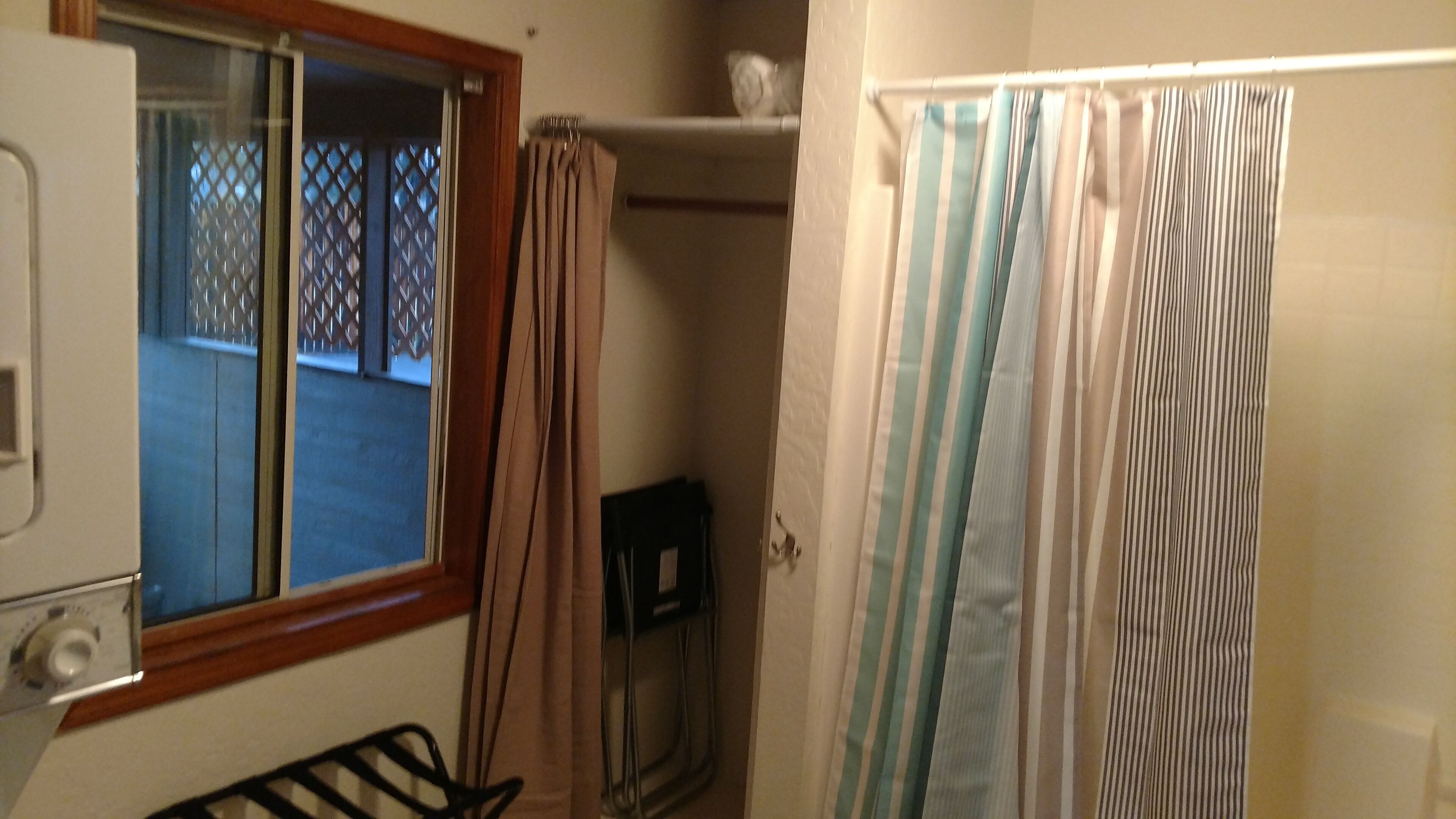 Een badkamer met douchegordijn, een raam en een handdoekhouder.